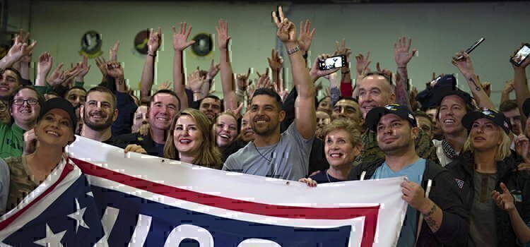 a group of people holding the USO flag together smiling