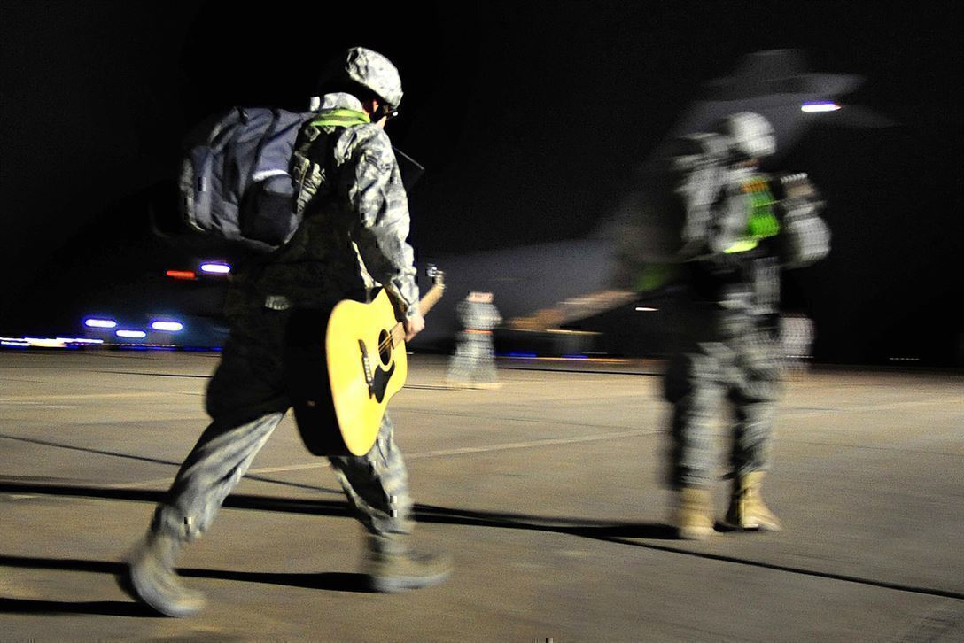 photo shows a soldier carrying a guitar to write a song about war