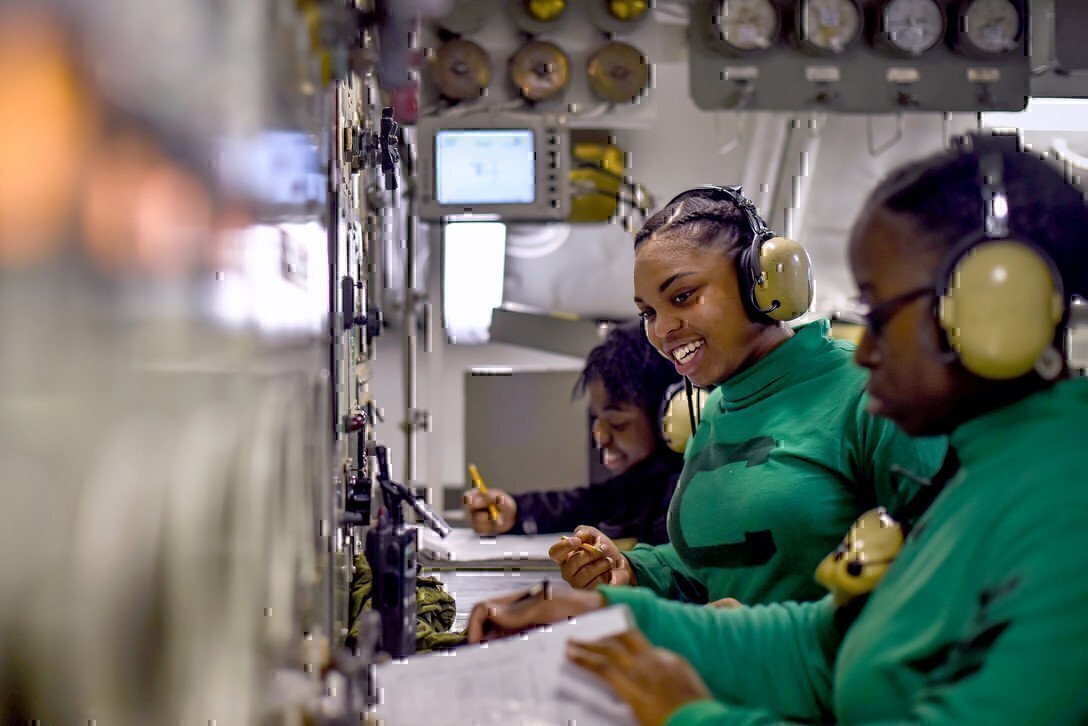 photo shows three female Navy members wearing headsets