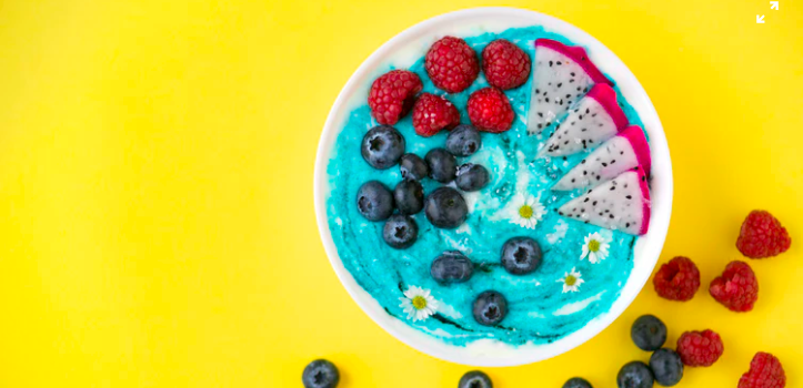 a bowl containing yogurt, blueberries and raspberries