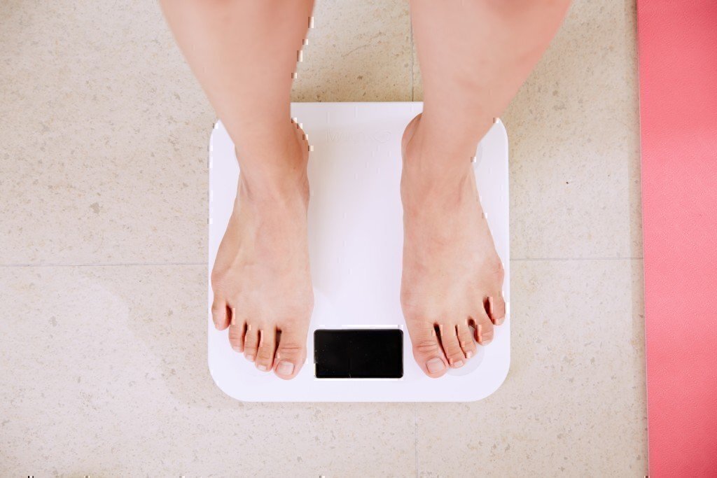 A person's feet as they stand on a white scale