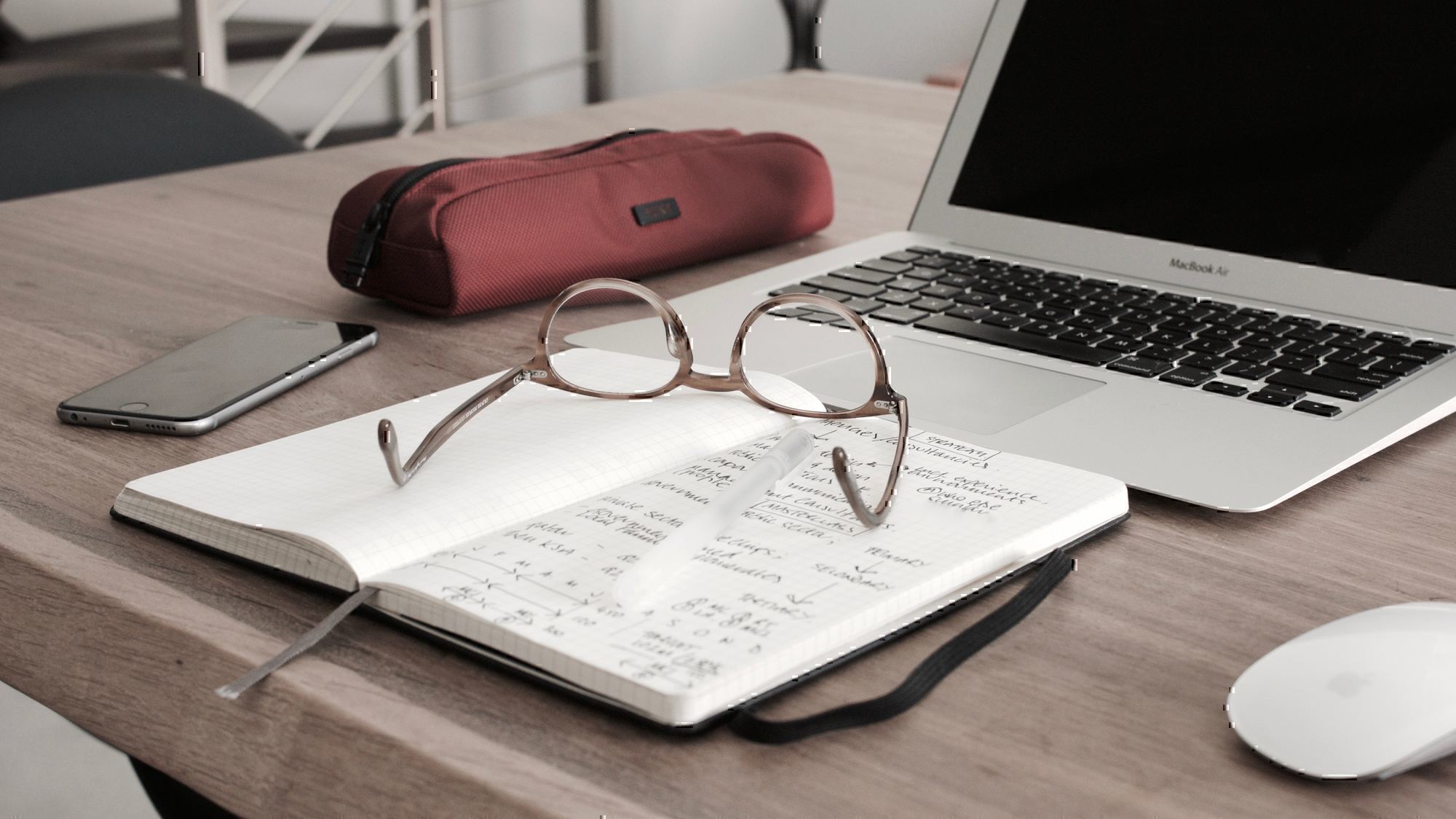 a pair of glasses sits on a notepad in front of a computer