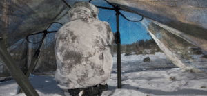 man-in-military-camo-sitting-in-snow-under-tent