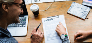 two people point to a paper contract on a table