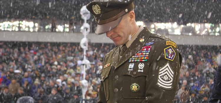 An army soldier stands in his dress green uniform