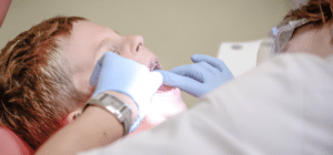 a dental assistant works on the mouth of a young patient