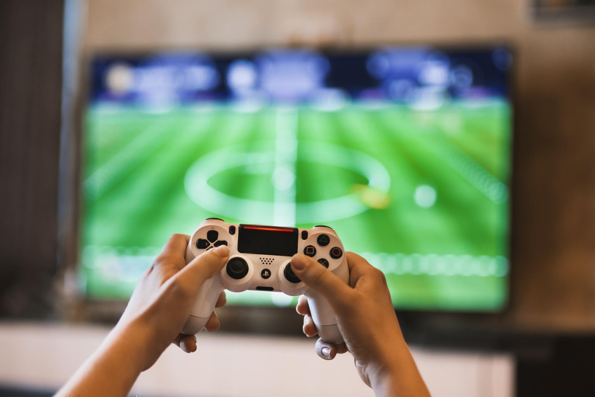 a person holds a video game controller in front of a television