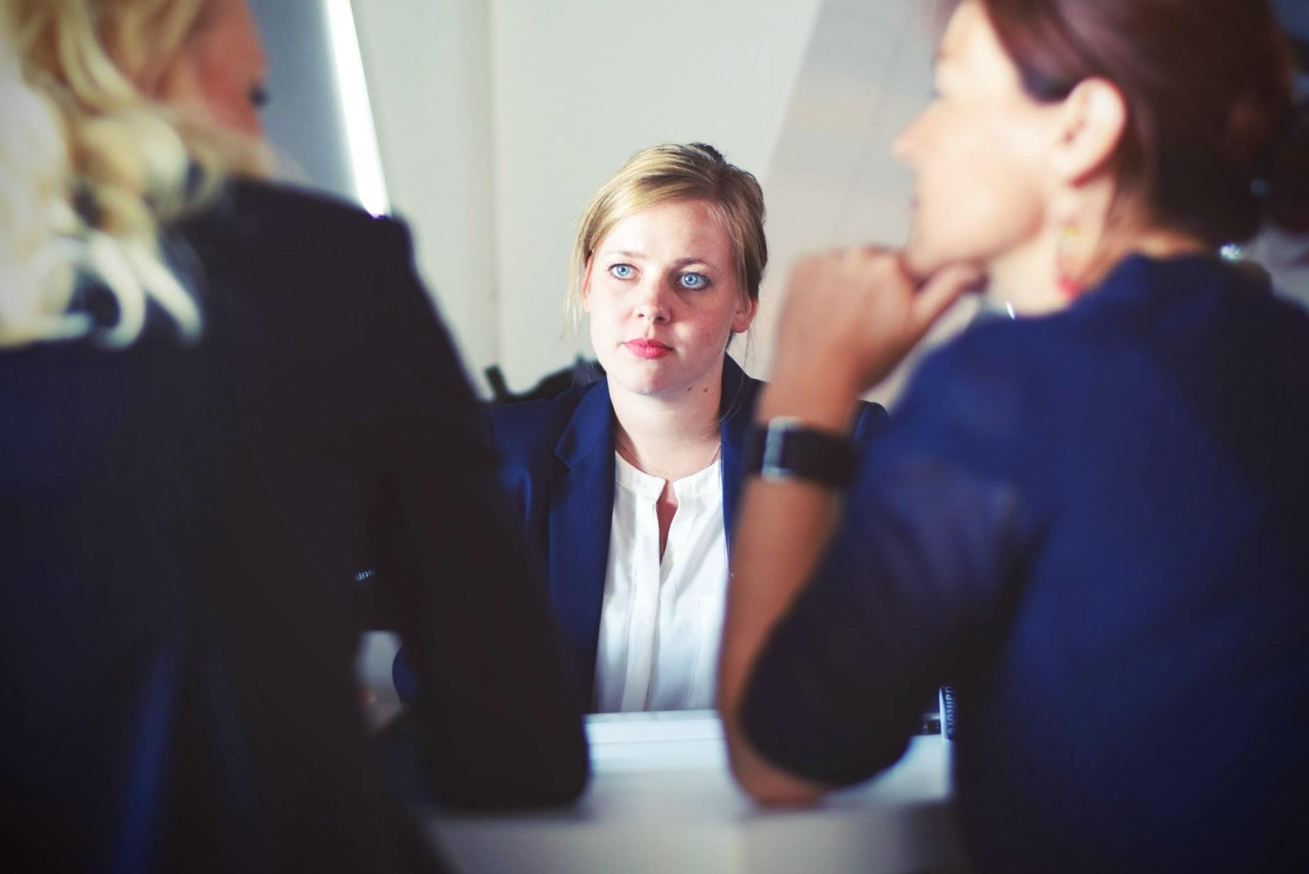 three women sit at a table during a job interview