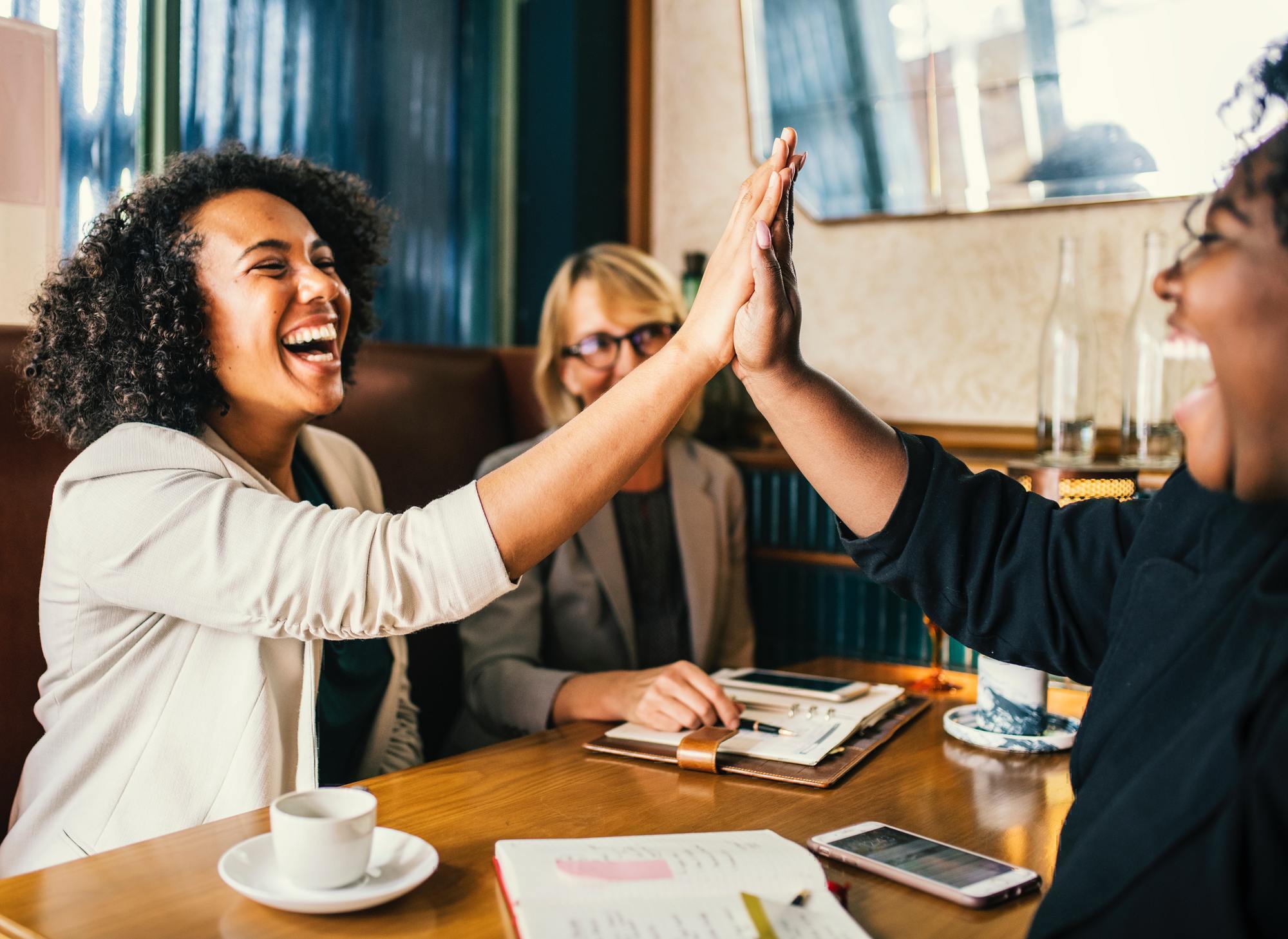 two women slap hands across a table