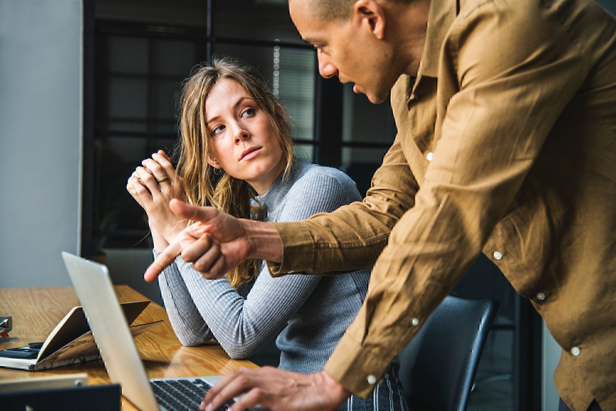 two colleagues talk by a computer