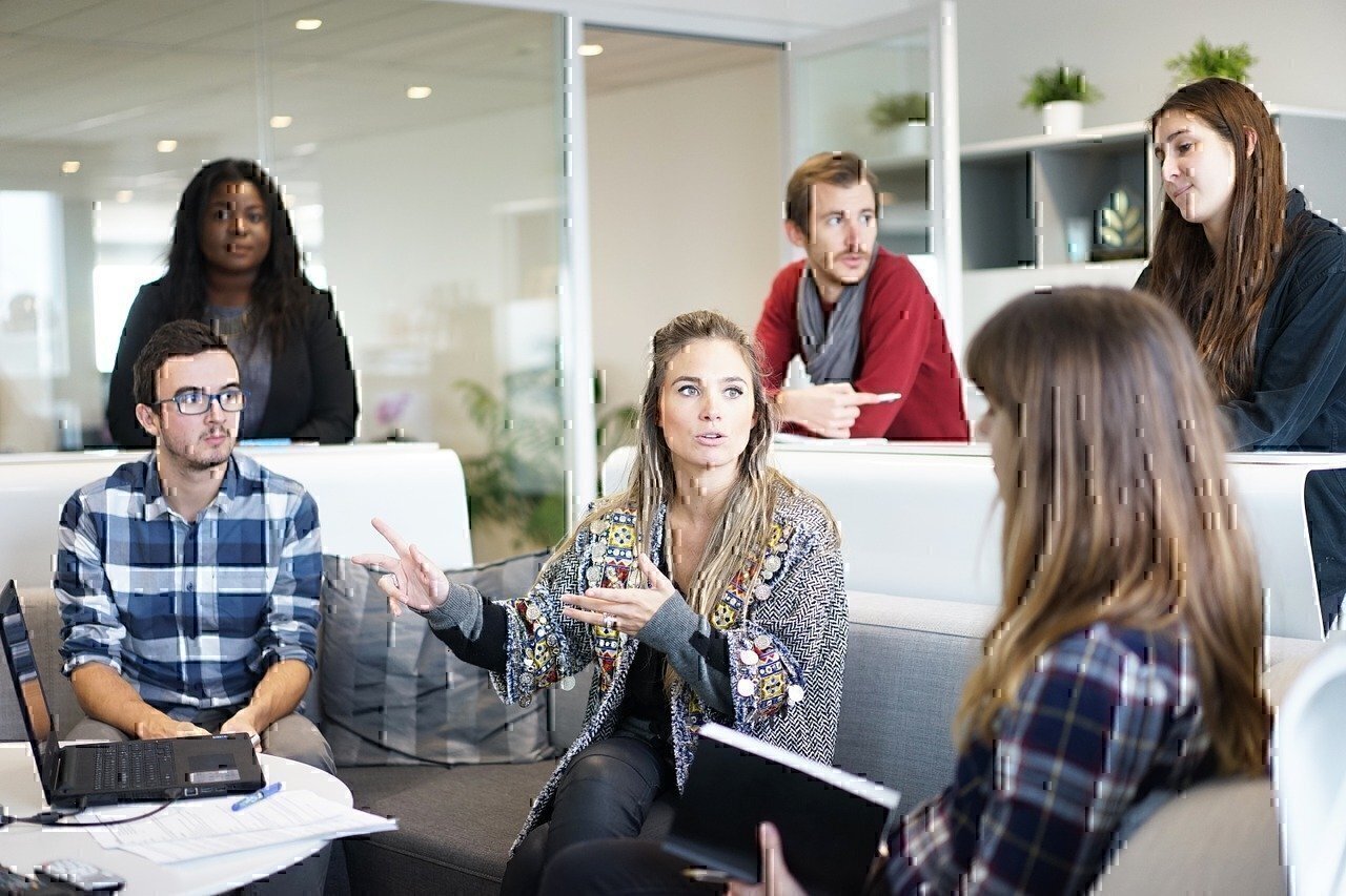 A woman talks to co-workers on a couch