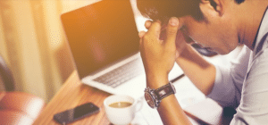 a man sits with his head in his hands over a computer
