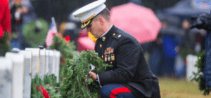 A Marine places a wreath on a tombstone