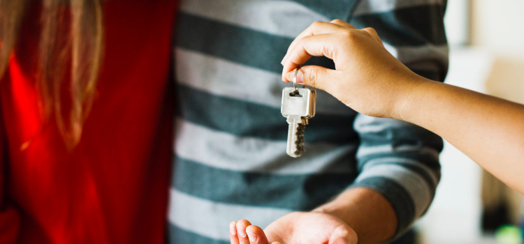 A real estate agent hands the keys to a home to a couple