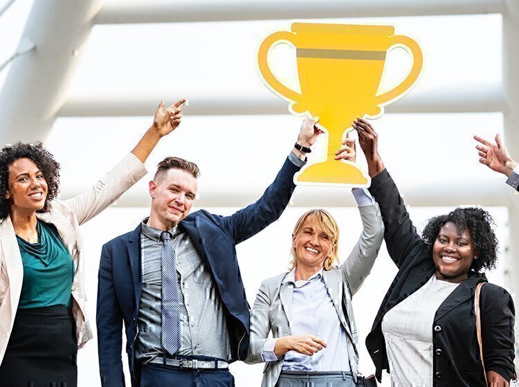 a group of people holding up a trophy sign in business formal clothing