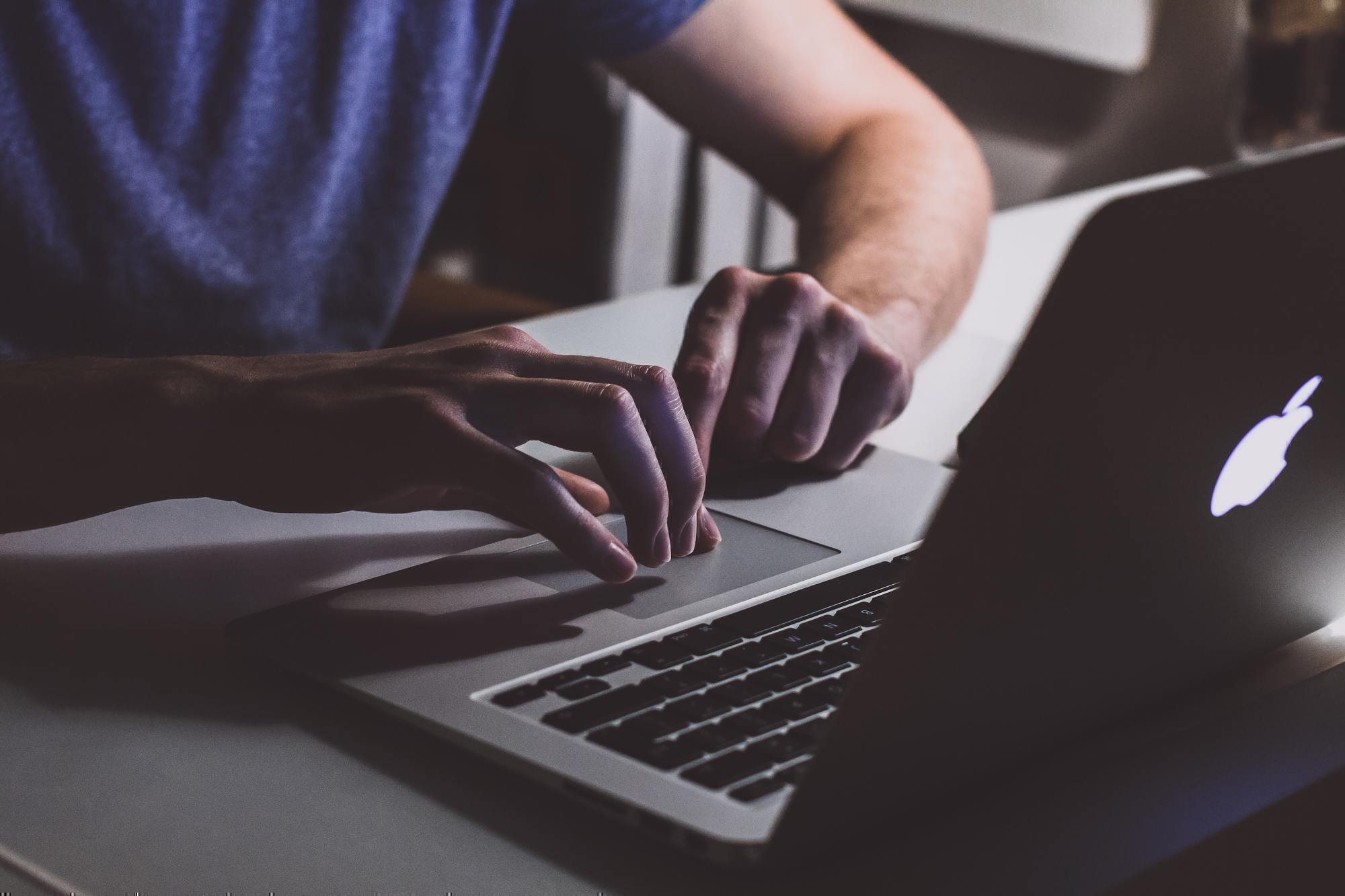 a person typing on an Apple computer