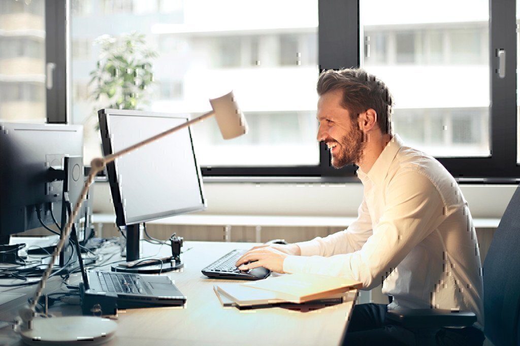 man smiling while working on a computer