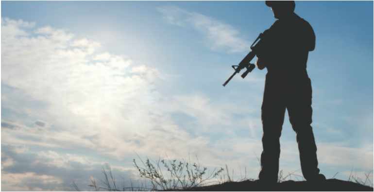 a man holding a rifle in the open