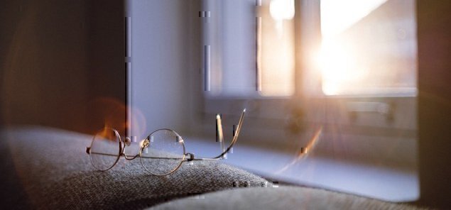 a pair of glasses on a desk with sunlight in the background