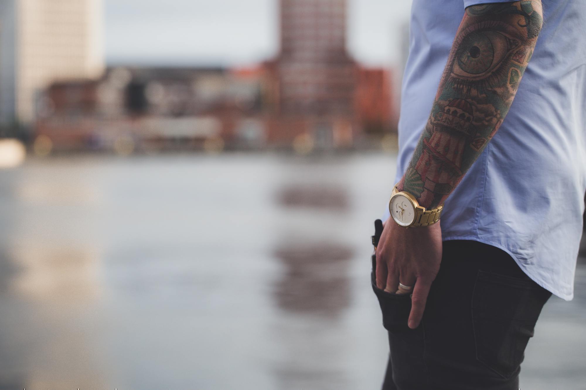 a man with an arm tattoo and a watch on