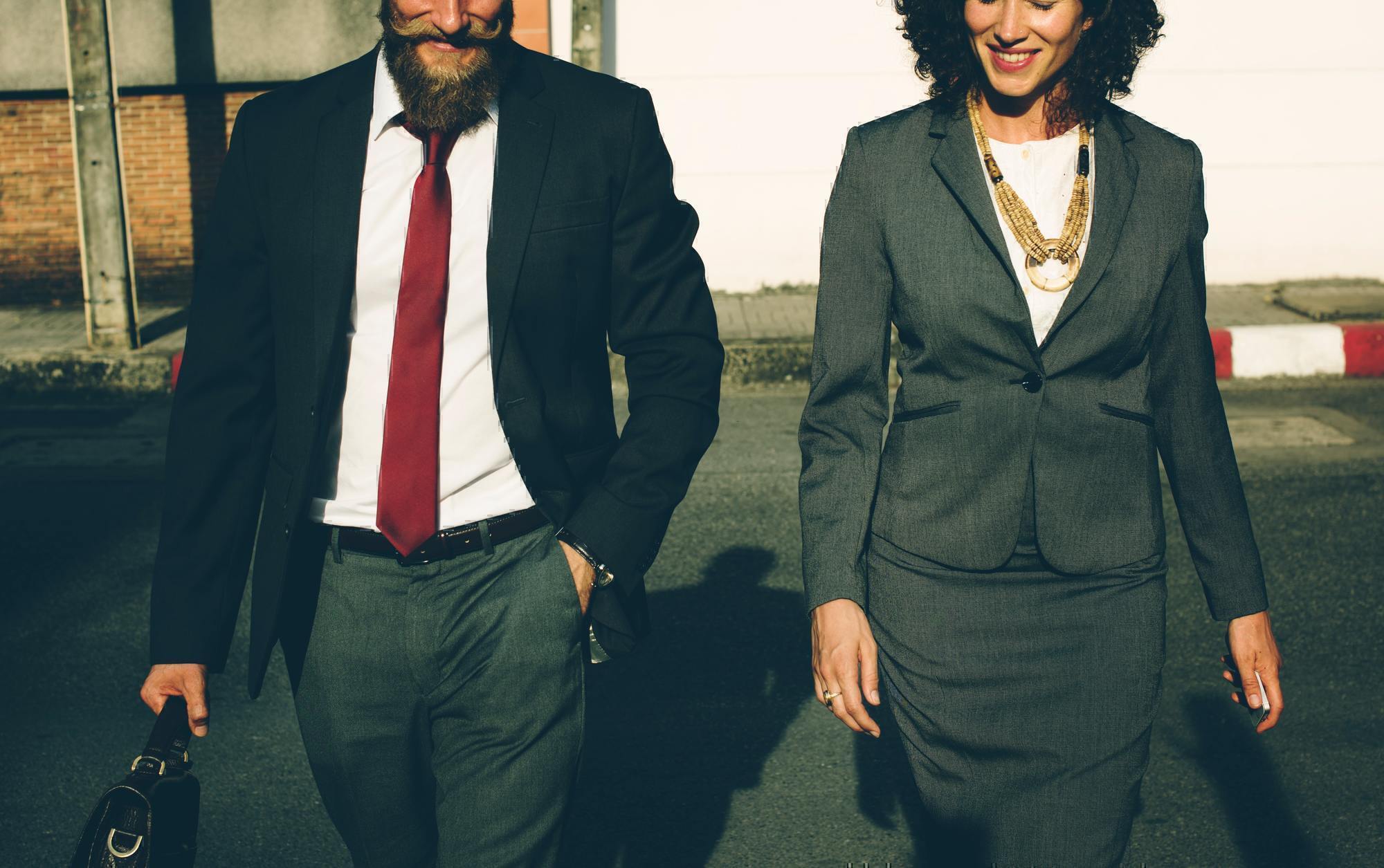 a man and woman walking in business formal attire