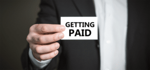 a picture of a man holding a card that says getting paid on it