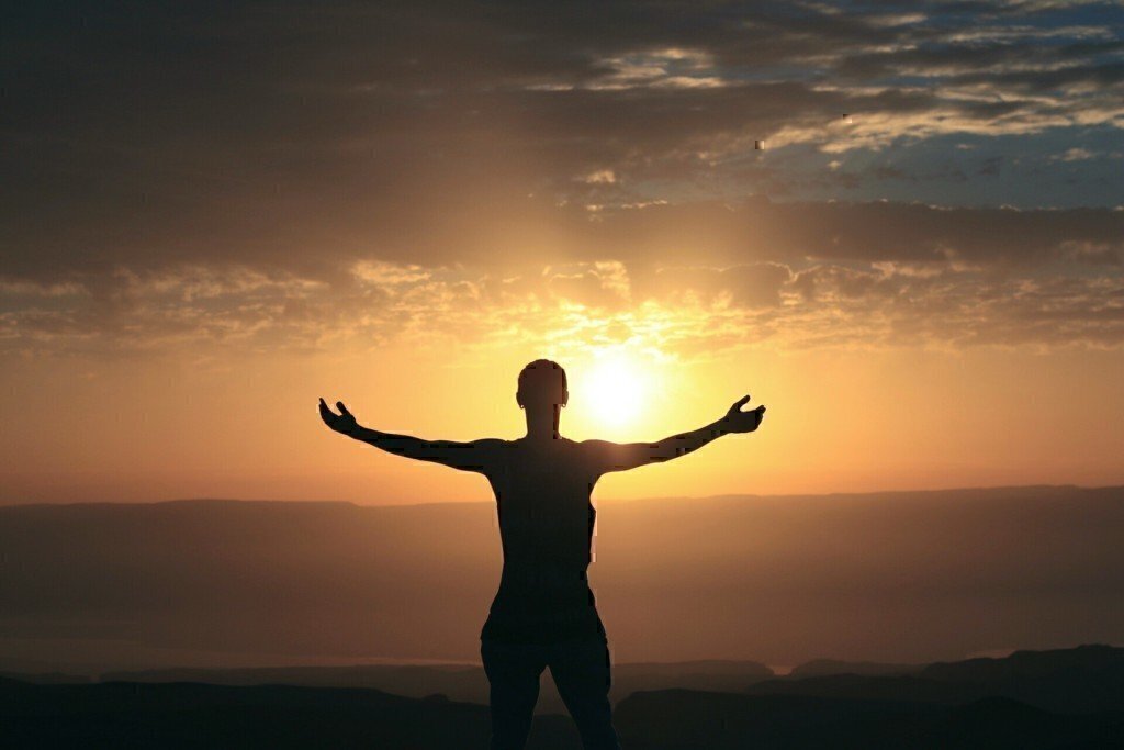 a man standing on a hill with a sunset