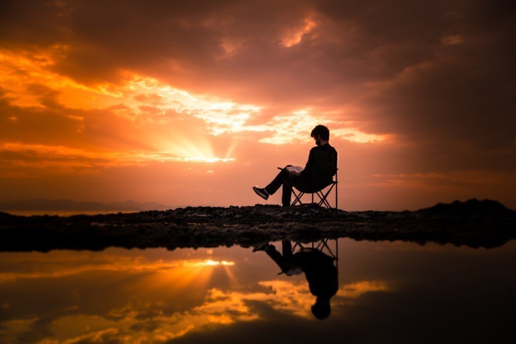 a person reading on a chair during sunset