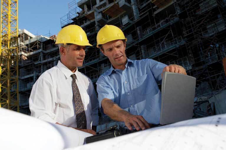 Two veterans working on a construction site reviewing their building plans.