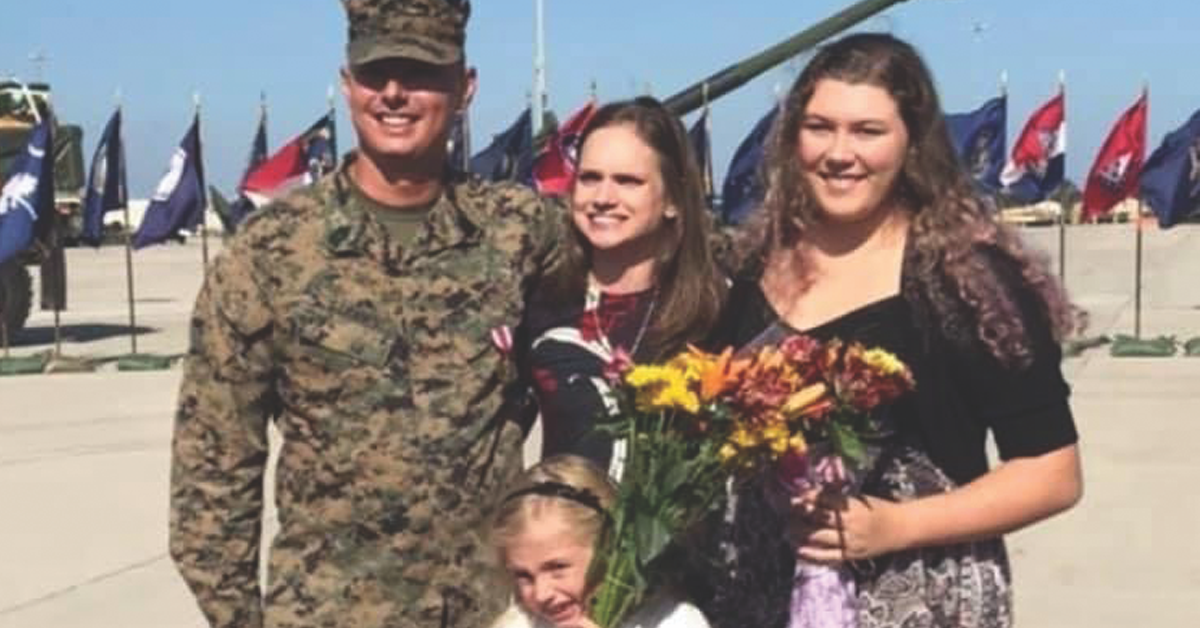 Aaron Strang, a retired Marine Corps master sergeant who used his military experience to create a seamless military transition, stands in uniform with him wife and two kids.